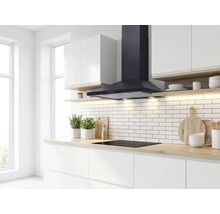 Cuisine moderne et lumineuse avec hotte aspirante décorative noire au-dessus d'une plaque à induction et crédence en carreaux de métro blancs.