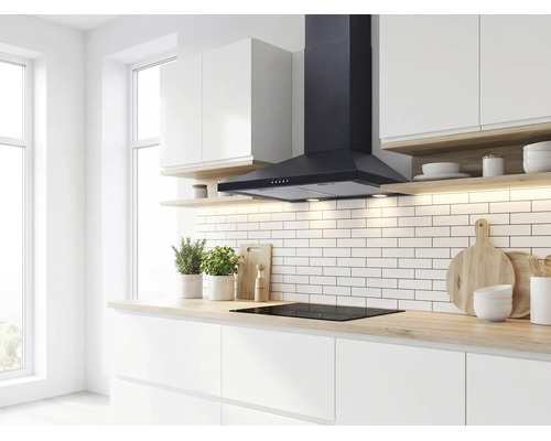 Cuisine moderne et lumineuse avec hotte aspirante décorative noire au-dessus d'une plaque à induction et crédence en carreaux de métro blancs.