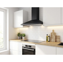 Moderne helle Küche mit schwarzer Kaminhaube, weißem Fliesenspiegel, Kochfeld, Einbaubackofen und Arbeitsplatte in Holzoptik.