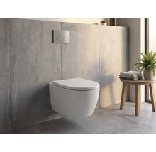 Wand-WC an engem modernen Buedzëmmer mat Betonoptik, Betätegungsklapp un der Mauer an engem Holzhocker mat Handdicher an enger Planz.