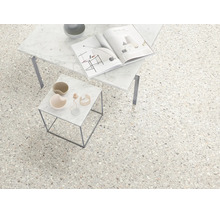 Carrelage de sol aspect terrazzo dans une pièce lumineuse et moderne avec deux tables d'appoint en marbre.