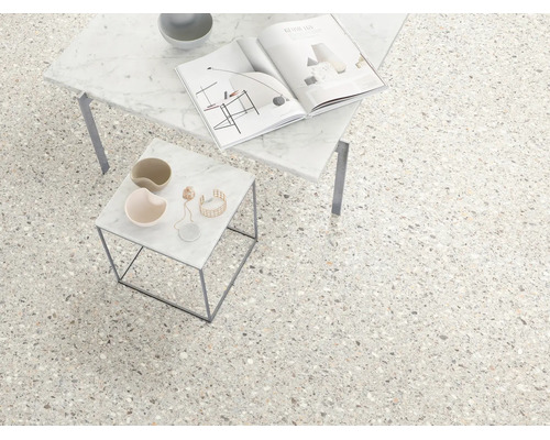 Carrelage de sol aspect terrazzo dans une pièce lumineuse et moderne avec deux tables d'appoint en marbre.