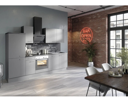 Bloc cuisine moderne gris de style loft avec appareils électroménagers devant un mur en briques avec enseigne au néon et table à manger.