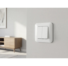 Double interrupteur blanc sur un mur clair dans une pièce lumineuse, meublée de façon moderne et organisée.