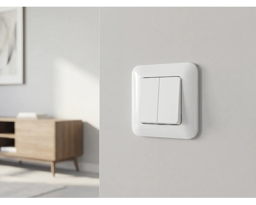 Double interrupteur blanc sur un mur clair dans une pièce lumineuse, meublée de façon moderne et organisée.