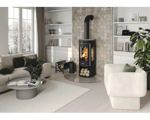Modernes Wohnzimmer mit schwarzem Kaminofen vor einer Natursteinwand, hellem Sofa, grauem Couchtisch und weißem Sessel.