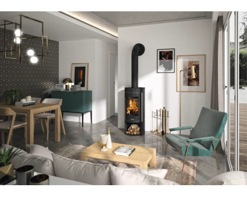 Modernes Wohnzimmer mit schwarzem Kaminofen mit brennendem Feuer, Holztisch, türkisem Sessel und hellen Wänden.