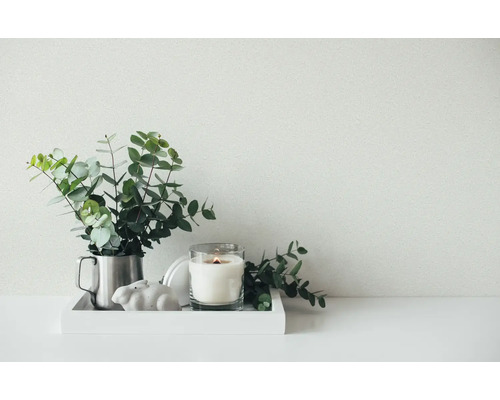 Arrangement clair et organisé sur un plateau blanc avec des branches d eucalyptus dans un pot en métal, une bougie allumée et un lapin en céramique.