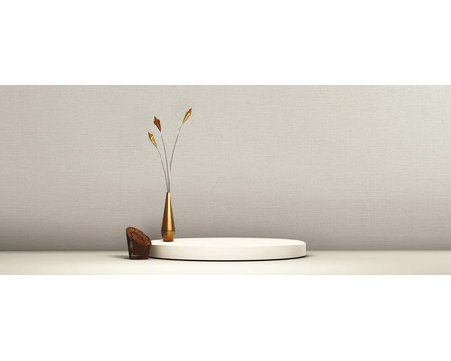Papier peint beige clair à structure fine dans une pièce minimaliste avec socle et vase décoratif.
