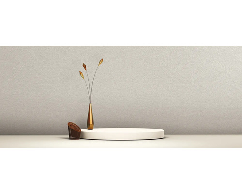 Mur texturé avec un podium rond, un vase doré élancé avec trois branches décoratives et un petit fauteuil tressé marron.
