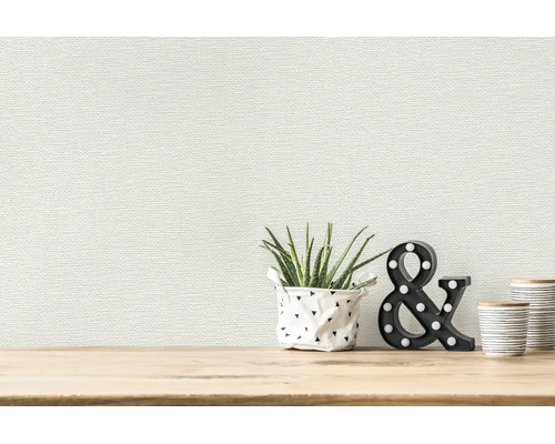 Papier peint structuré avec un motif horizontal fin derrière une plante et de la décoration sur une surface en bois dans une pièce lumineuse.