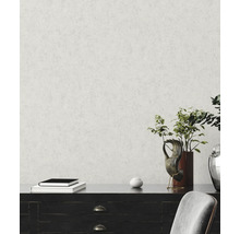 Papier peint intissé avec structure de crépi fine sur un mur derrière un buffet sombre avec décoration et une plante.