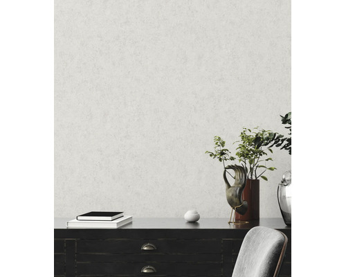 Papier peint intissé avec structure de crépi fine sur un mur derrière un buffet sombre avec décoration et une plante.