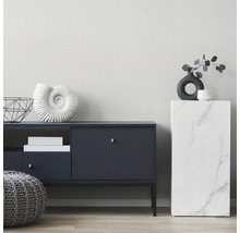 Salon moderne avec buffet bleu foncé, pouf en tricot gris et colonne aspect marbre devant un mur clair structuré.