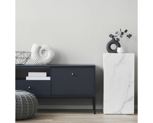 Salon moderne avec buffet bleu foncé, pouf en tricot gris et colonne aspect marbre devant un mur clair structuré.