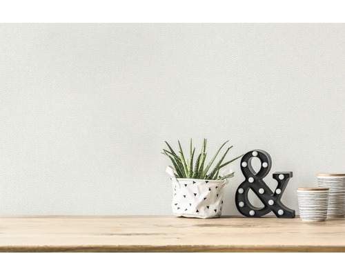 Papier peint texturé dans une pièce lumineuse et moderne derrière une étagère en bois avec une petite plante, une esperluette et des bocaux.