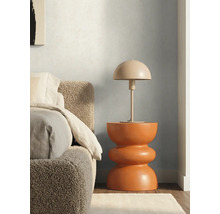 Lampe à poser en forme de champignon sur une table d'appoint sculpturale moderne à côté d'un lit avec une tête de lit texturée.