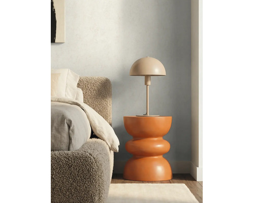 Lampe à poser en forme de champignon sur une table d'appoint sculpturale moderne à côté d'un lit avec une tête de lit texturée.