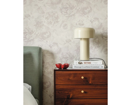 Chambre lumineuse avec papier peint intissé à fleurs, table de chevet en bois, lampe à poser beige et tête de lit verte.
