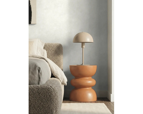 Chambre moderne avec peinture murale texturée, lit en bouclé et lampe à poser en forme de champignon sur une table d'appoint sculpturale.