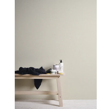 Mur intérieur peint en beige clair, décor minimaliste comprenant un banc en bois et des produits de soin.