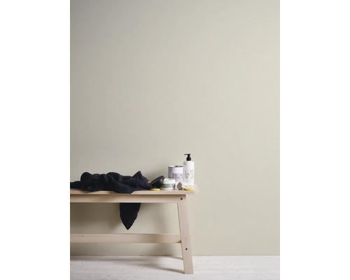 Mur intérieur peint en beige clair, décor minimaliste comprenant un banc en bois et des produits de soin.