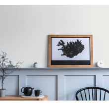 Carte de l'Islande encadrée dans un cadre en bois sur une tablette murale au-dessus d'un lambris bleu clair décoré.