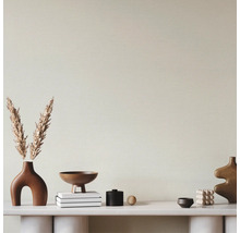 Papier peint texturé clair dans une pièce moderne avec console blanche et décoration aux tons terreux.