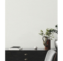 Papier peint texturé clair dans un bureau derrière un bureau sombre avec décoration et une chaise grise.