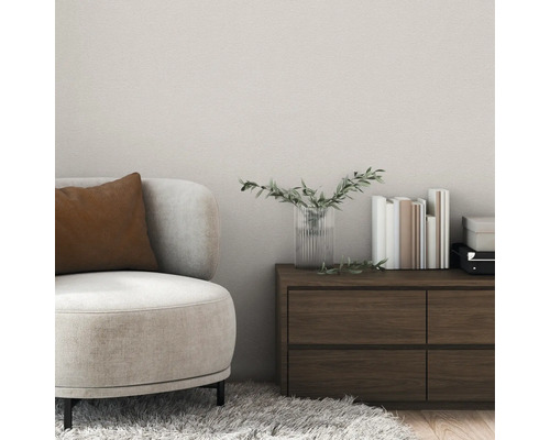 Salon moderne avec revêtement mural texturé, fauteuil beige avec coussin marron et commode en bois foncé.