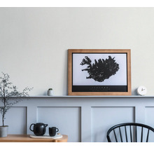 Cadre photo en bois avec une carte de l'Islande en noir et blanc sur une étagère dans une pièce lumineuse et minimaliste.