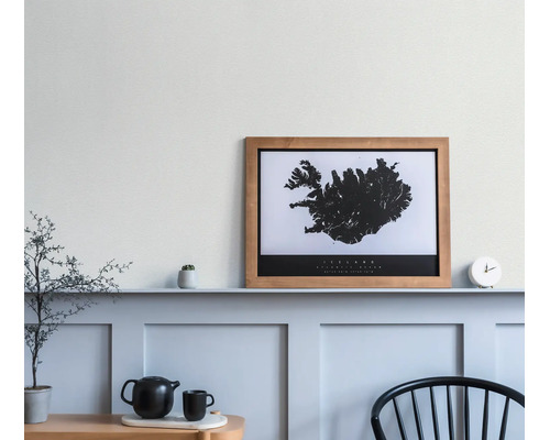 Cadre photo en bois avec une carte de l'Islande en noir et blanc sur une étagère dans une pièce lumineuse et minimaliste.