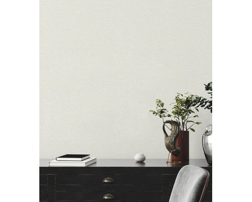 Papier peint intissé structuré aspect lin sur un mur derrière un buffet avec décoration et livres.