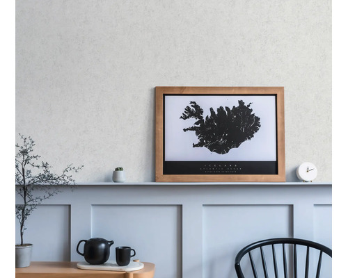 Une carte murale encadrée de l'Islande posée sur une étagère dans une pièce minimaliste avec des boiseries, une horloge et une théière.
