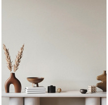 Mur texturé derrière une console blanche avec des objets décoratifs tels que des vases, des bols et des livres.