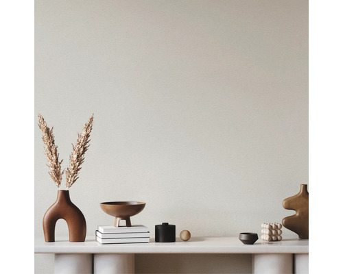 Mur texturé derrière une console blanche avec des objets décoratifs tels que des vases, des bols et des livres.