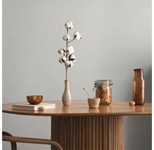 Table ronde en bois avec un pied colonne cannelé, décorée d'un vase avec une branche de coton, d'un bocal en verre, d'une bouteille et d'un livre.
