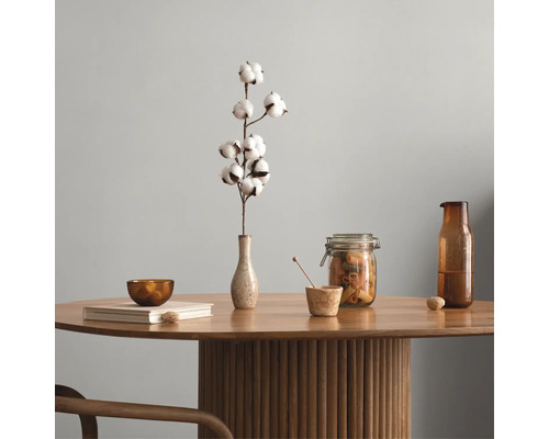 Table ronde en bois avec un pied colonne cannelé, décorée d'un vase avec une branche de coton, d'un bocal en verre, d'une bouteille et d'un livre.