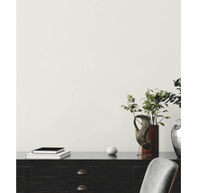 Scène minimaliste lumineuse avec un mur clair, un bureau en bois sombre avec décoration, livres et une plante dans un vase.