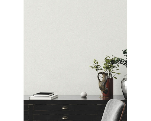 Pièce lumineuse avec papier peint texturé, bureau en bois sombre, plantes et objets décoratifs.
