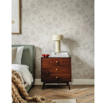Papier peint floral subtil avec motifs de roses dans une chambre avec table de chevet en bois foncé, lampe crème et tête de lit verte.