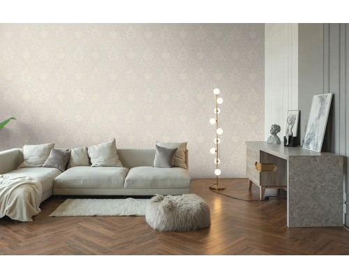 Salon lumineux avec papier peint à motifs discrets, canapé clair, lampadaire moderne et parquet à chevrons.