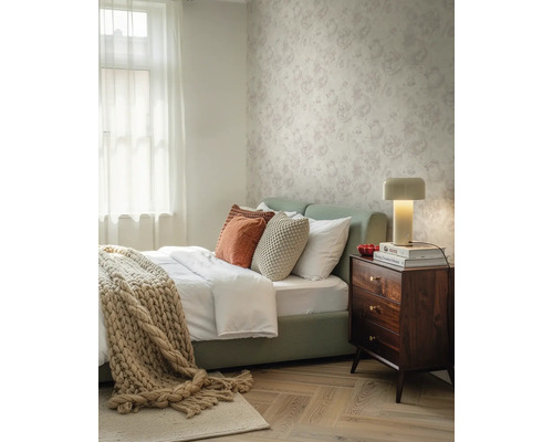 Papier peint intissé à motif floral dans une chambre lumineuse avec table de chevet en bois et parquet.