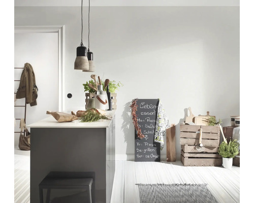 Cuisine lumineuse avec îlot gris, suspensions en béton, ustensiles en bois, tableau noir et caisses en bois sur un sol clair.
