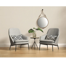 Salon lumineux avec deux fauteuils gris, coussins à motifs géométriques, une petite table d'appoint ronde et un miroir mural rond.
