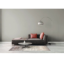 Salon moderne avec canapé en tissu foncé, coussins rouges, table basse ronde en marbre, tapis à motifs et lampadaire à arc argenté.