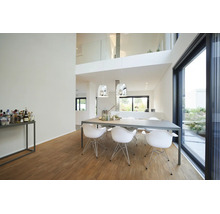 Salle à manger moderne et lumineuse avec table grise, chaises blanches, parquet en bois et grandes baies vitrées.