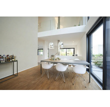 Salle à manger moderne et lumineuse avec grande table grise, chaises design blanches, suspensions chromées et parquet devant une baie vitrée.