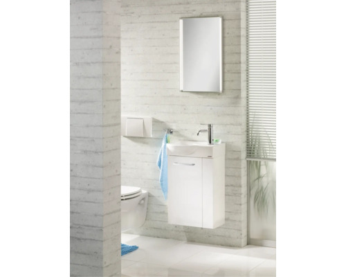Toilettes d'invités lumineuses avec meuble sous vasque blanc, vasque en céramique, robinet chromé, miroir éclairé et WC suspendu.