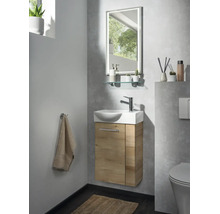 Salle de bains d'invités moderne avec petit lavabo, meuble sous-vasque aspect bois, robinet chromé et miroir éclairé.